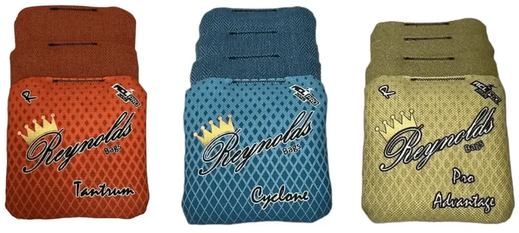 A display of three different Reynolds cornhole bags, each with unique designs and colors. Tantrum in orange, Cyclone in teal, Pro Advantage in gold, a popular bag for advanced players, These bags are designed for different playstyles, giving cornhole players a variety of performance options.