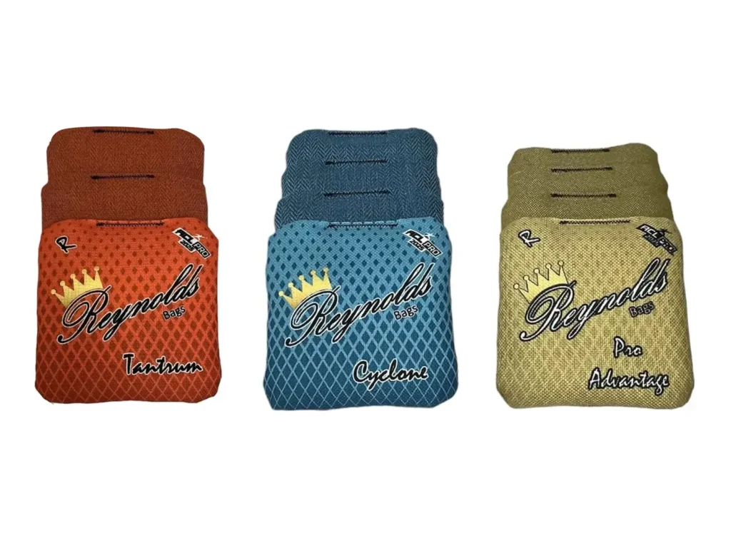 A display of three different Reynolds cornhole bags, each with unique designs and colors. Tantrum in orange, Cyclone in teal, Pro Advantage in gold, a popular bag for advanced players, These bags are designed for different playstyles, giving cornhole players a variety of performance options.