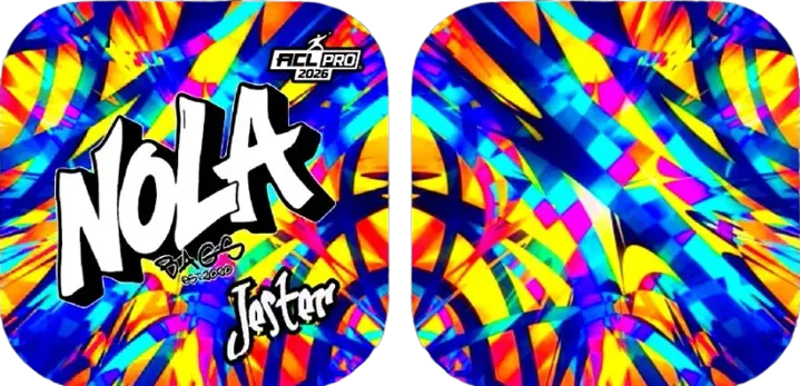 Two vibrant Nola Bags Cornhole bags with an abstract, colorful pattern of blue, yellow, and pink hues. The left bag features "NOLA" in a large white graffiti-style font with a black outline, and "Jester" in a smaller white script below it. Both bags have a small "ACL PRO 2026" logo at the top.