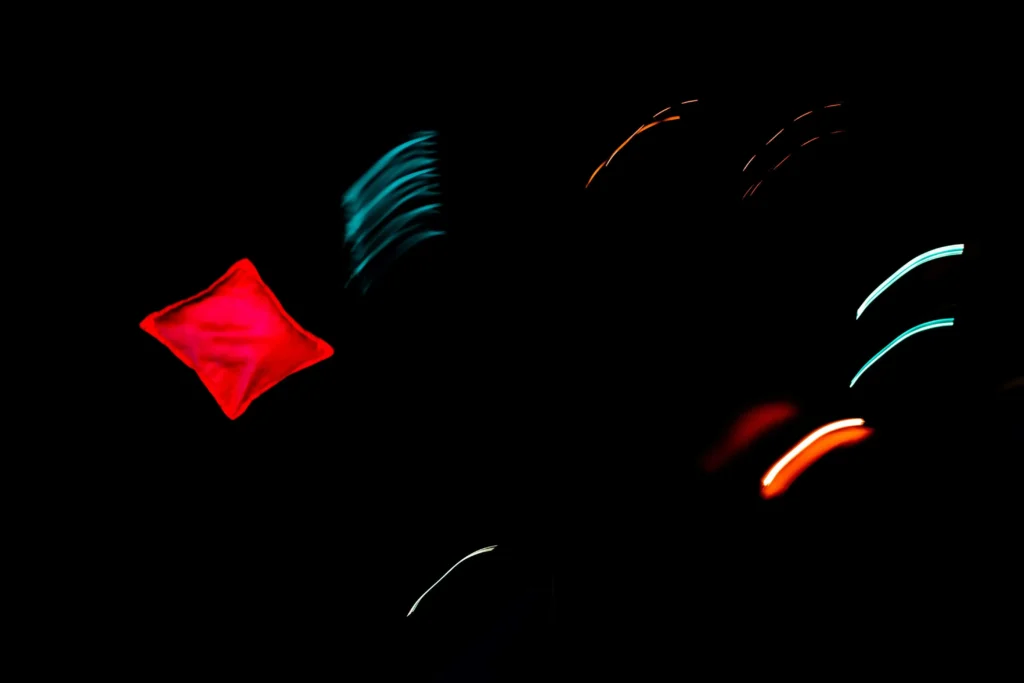 Image of a cornhole bag flying in the air with some pretty colorful lights used a cover of cornhole terminology