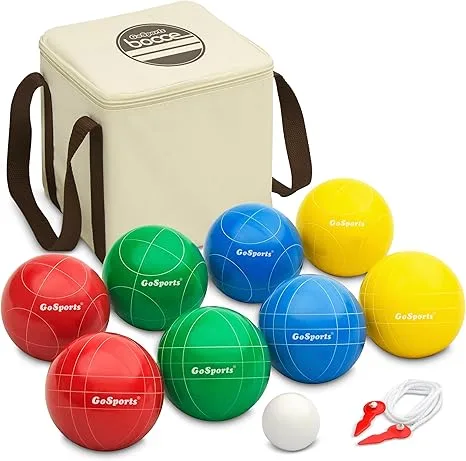 A GoSports Bocce Ball set is displayed, featuring a cream-colored carrying bag with brown handles. Six large bocce balls are arranged in front of the bag: two red, two green, and two blue, all with "GoSports" printed on them and white scoring lines. There are also two yellow bocce balls without scoring lines, a small white pallino ball, and a white rope with red clips, likely for measuring distances.